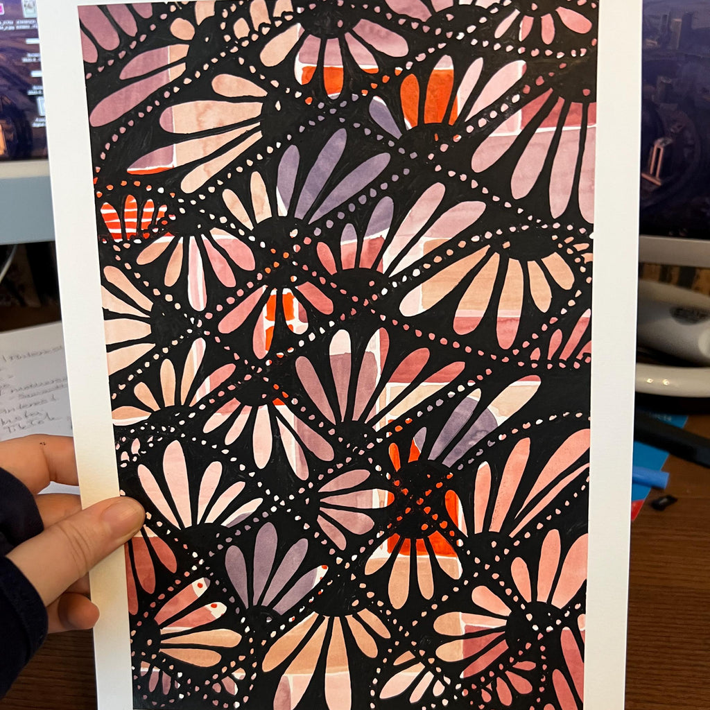 Hand holding a card with a colorful geometric pattern against a blurred indoor background